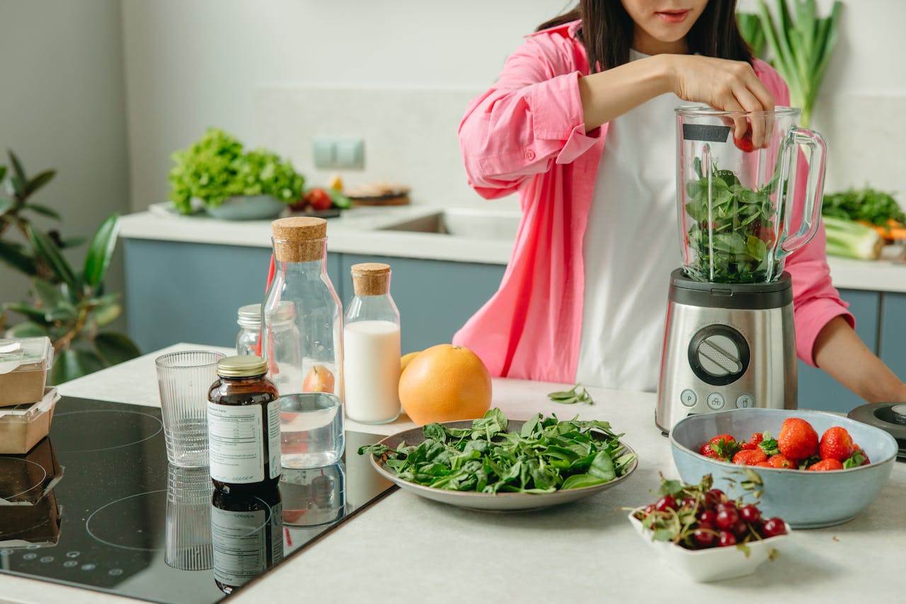 services-02 Woman in pink sleeve blending fresh fruits and veggies for a healthy smoothie.