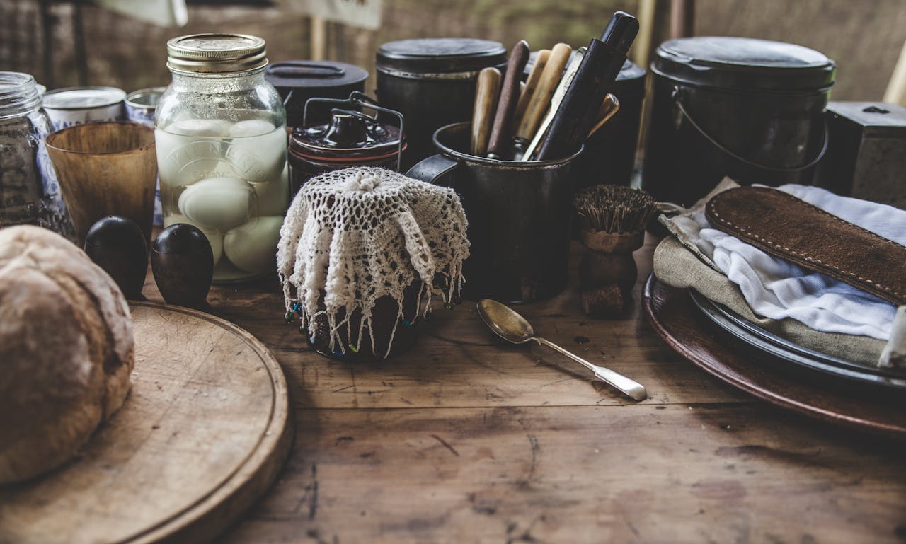 hero-contact A rustic kitchen scene featuring pickled eggs, bread, and kitchenware on a wooden table.