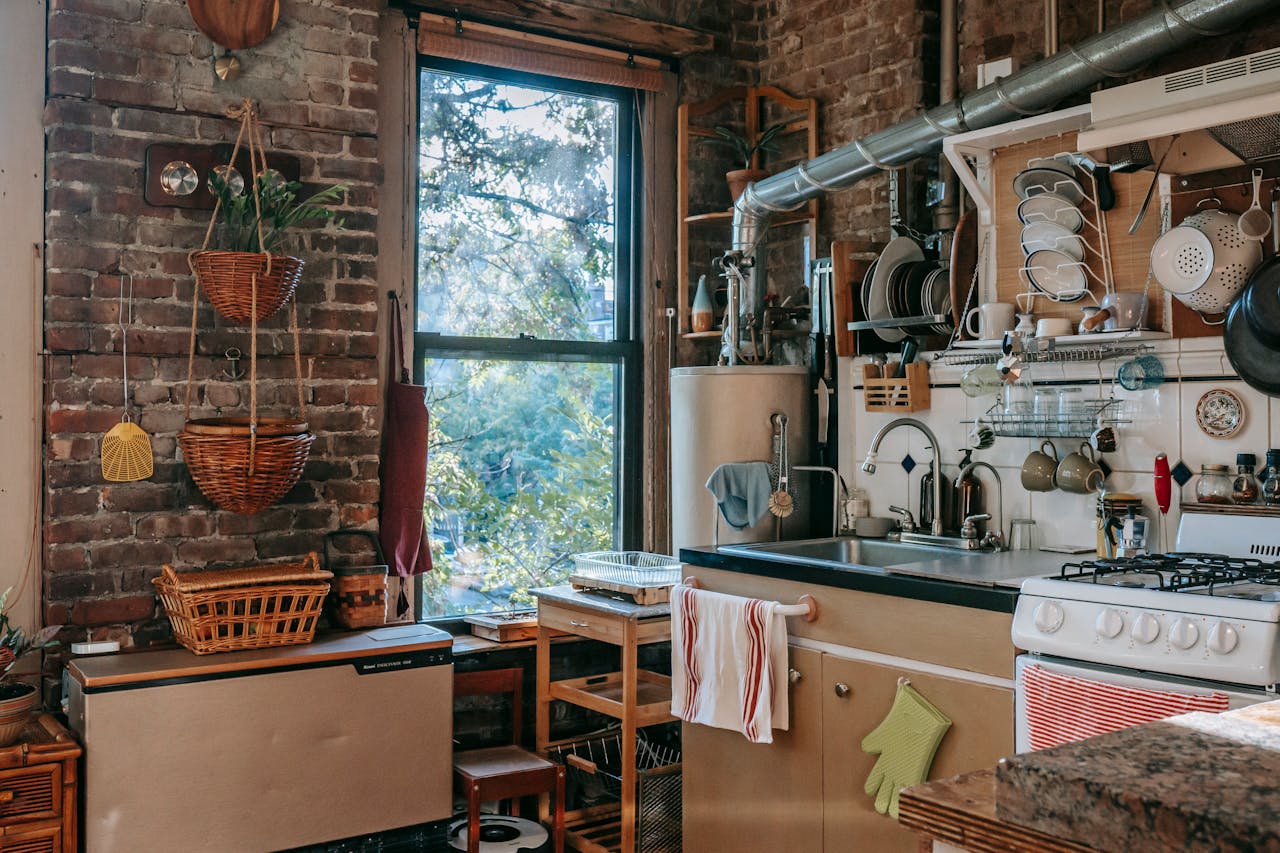 hero-about Charming rustic kitchen featuring wooden decor, exposed brick, and appliances with a sunlit window view.
